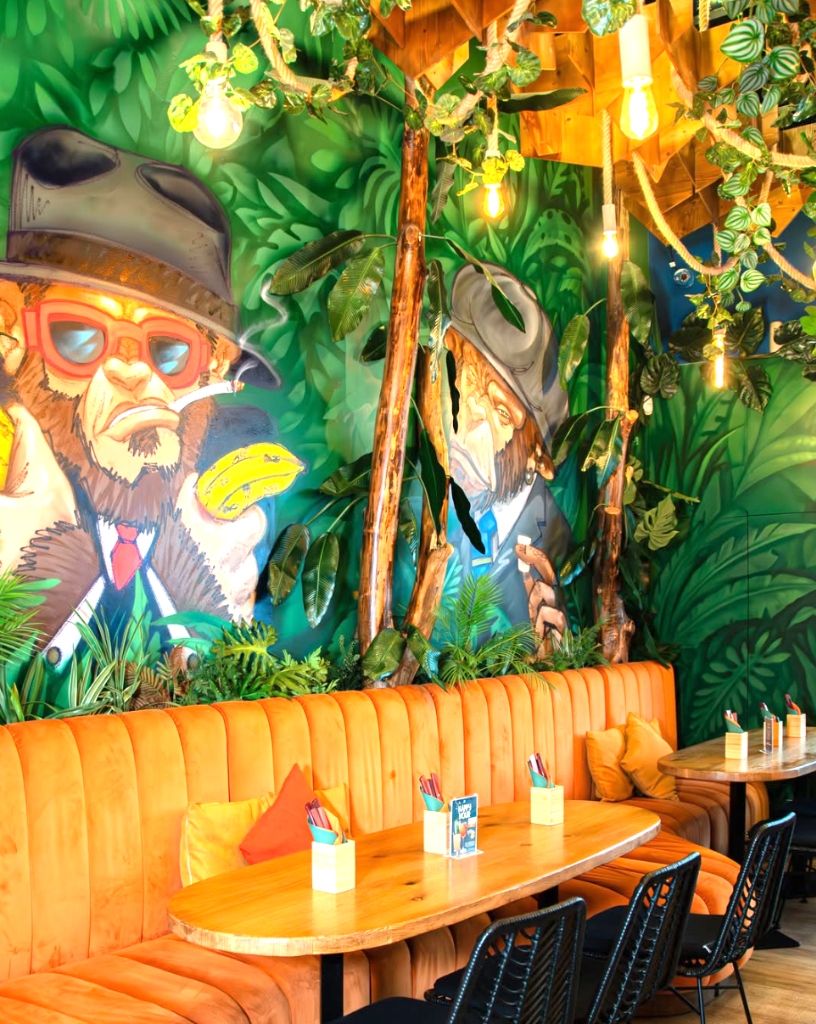 Mesa de Jantar com Sofá Aveludado Laranja e Mural no El Clan